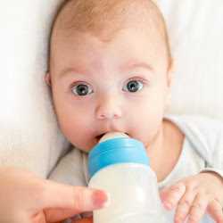 Малышу дают бутылочку Малыша кормят из бутылки