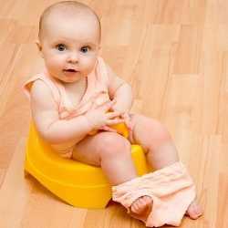 Ребенок и пластмассовый горшок Маленькая девочка сидит на пластмассовом горшке