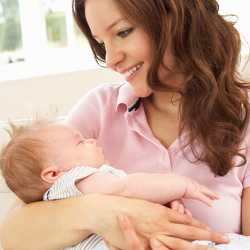 Ребенок на руках у мамы Мама укачивает ребенка