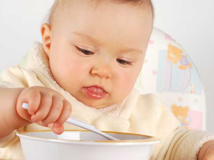 Ребенок за приемом пищи Маленький ребенок кушает кашу