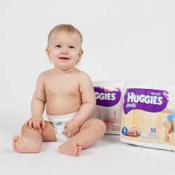Мальчик и упаковки Huggies Мальчик сидит рядом с упаковками подгузников Huggies