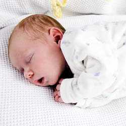 Малыш спит на боку Новорожденный малыш спит на боку