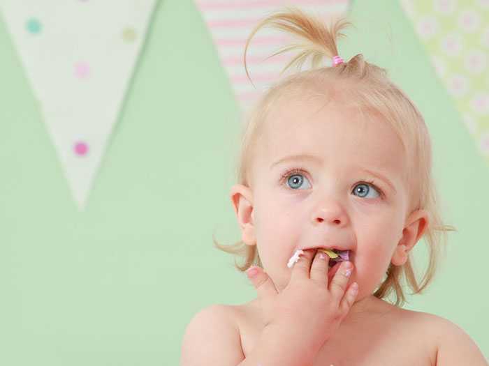 Девочка с рукой во рту Ребенок часто пробует все, что попадается под руку