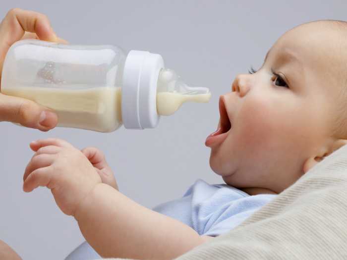 Малыш ест из бутылки Процесс кормления малыша из бутылки
